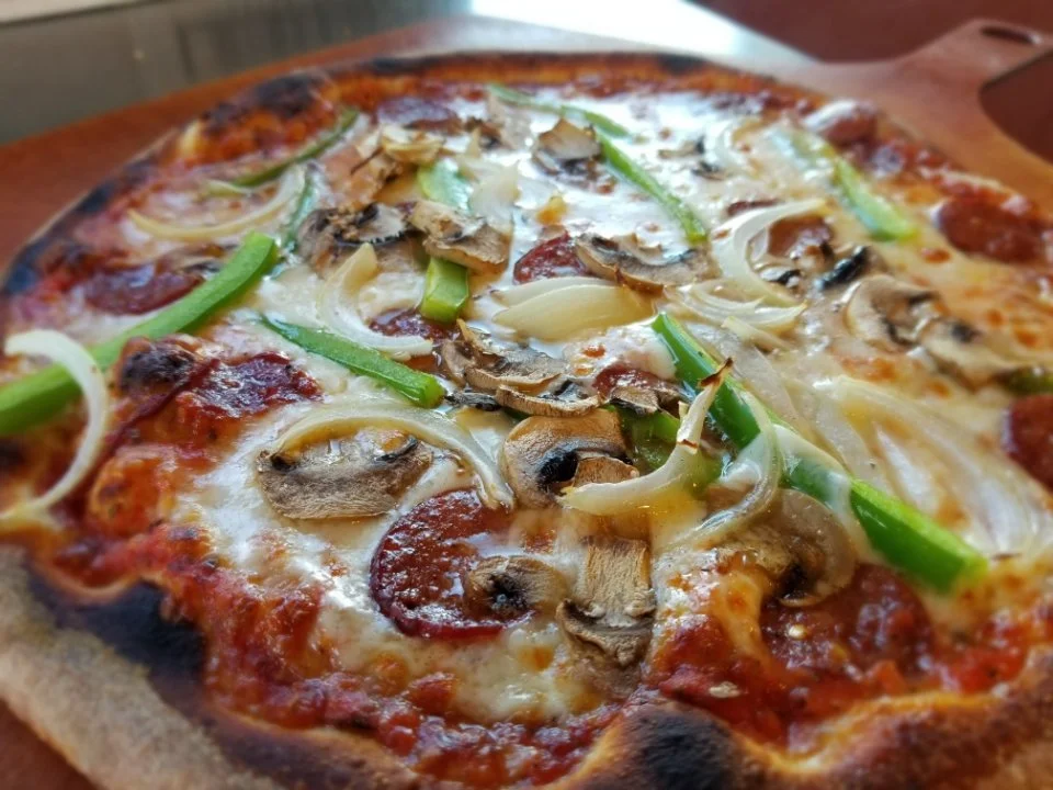Close-up of a pizza topped with mushrooms, green peppers, onions, pepperoni, and melted cheese.