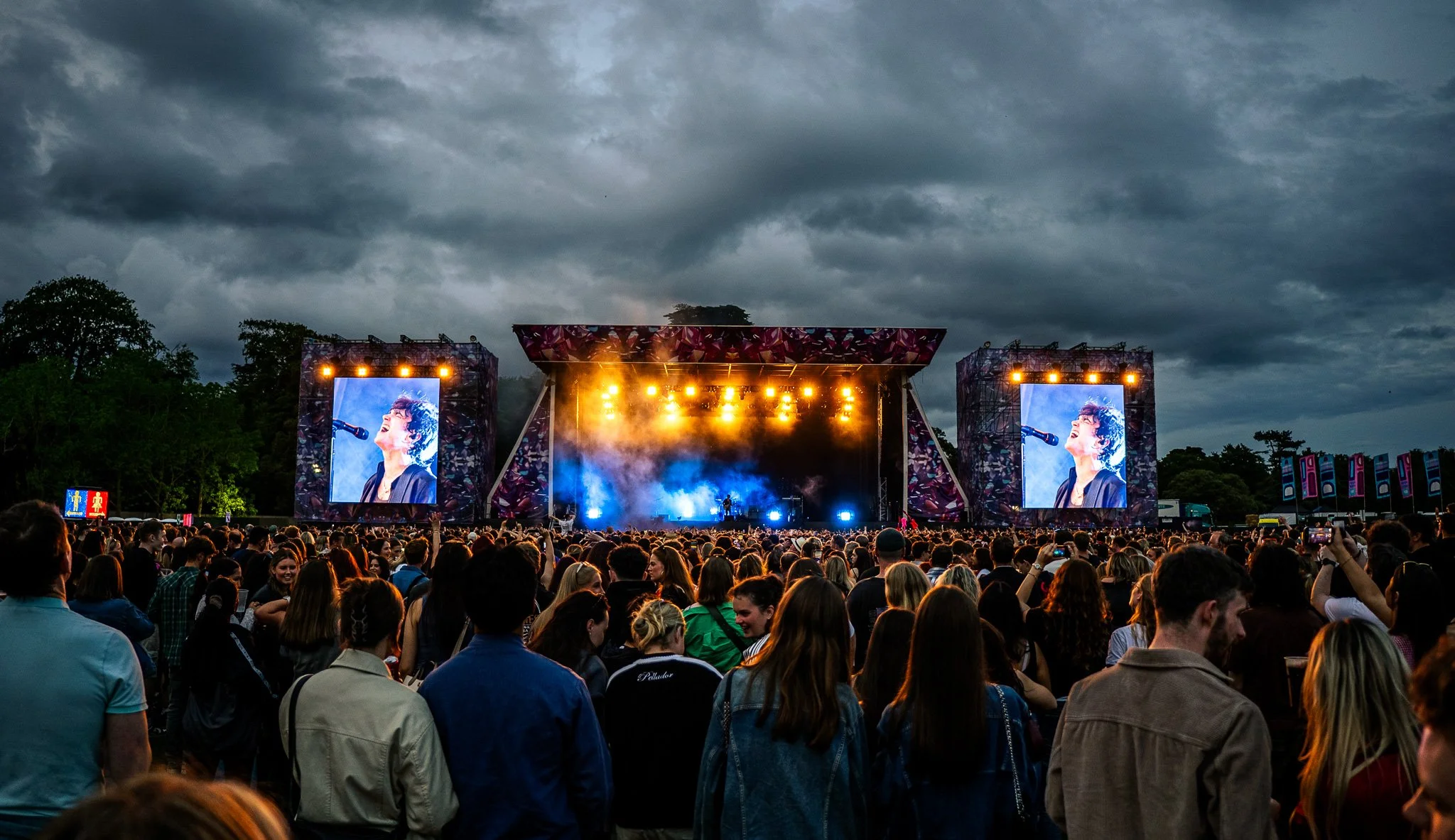 Crowd watching a concert with large screens and stage lights, cloudy sky in the background. Irish band Inhaler playing to a big crowd in St. Annes. Music Photography. 