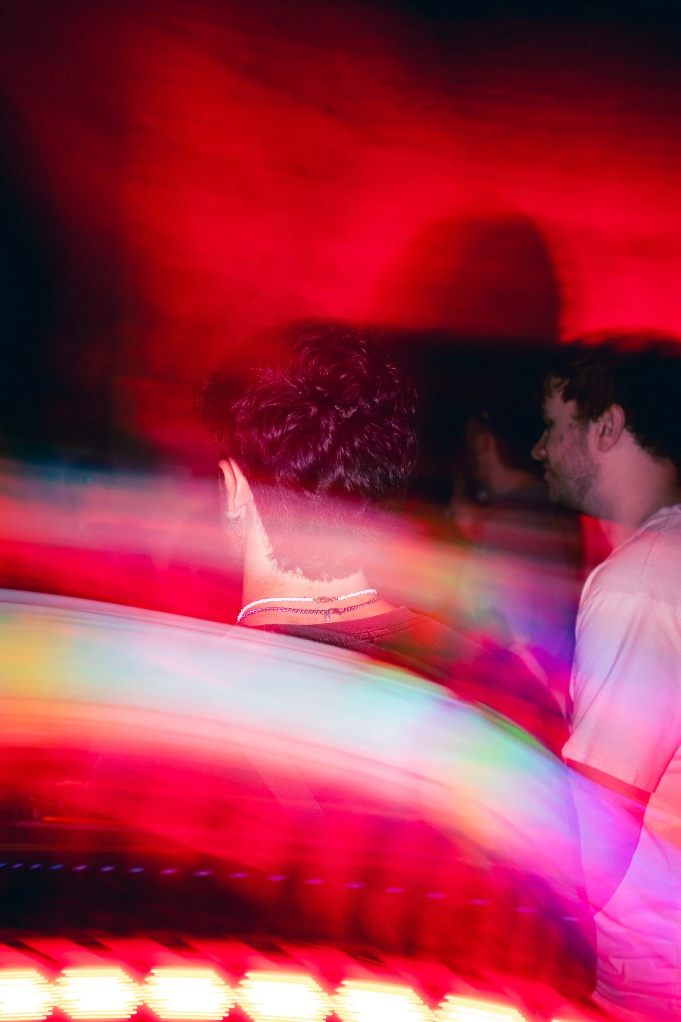 People in an outdoor rave or party environment with colorful light streaks and movement.