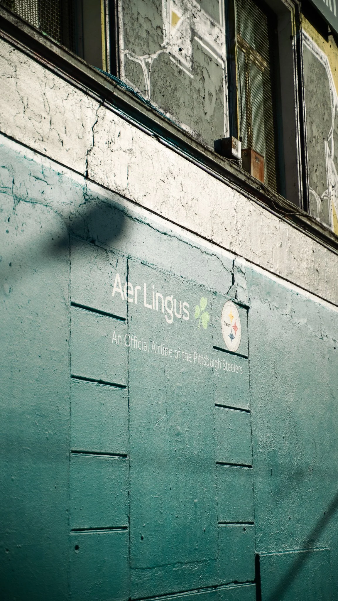 A green wall with a sign that reads 'Ari Lingus' and 'An Official Airname of the Pittsburgh Steelers,' including the Pittsburgh Steelers logo.