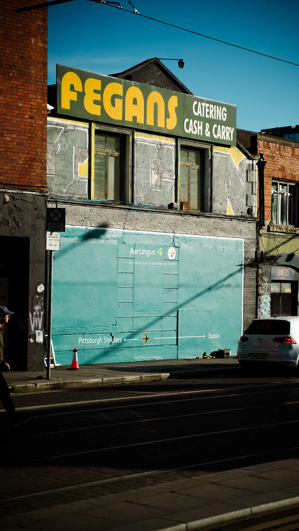 Street Mural done by Sean Atmos, Commissioned by Aer Lingus, for Collectiv Marketing. Promoting the NFL in Dublin. A mural of the Pittsburgh Steelers logo and a sign for Aer Lingus airline with an airplane graphic pointing toward Dublin.