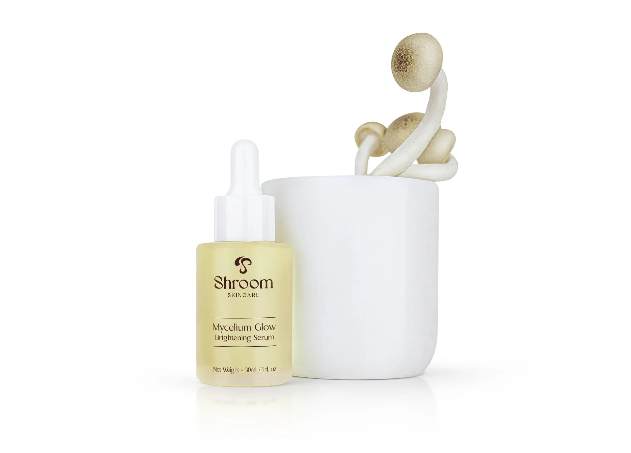 A bottle of Shroom Skincare Mycelium Glow Brightening Serum and a white ceramic pot with mushroom-like objects inside.