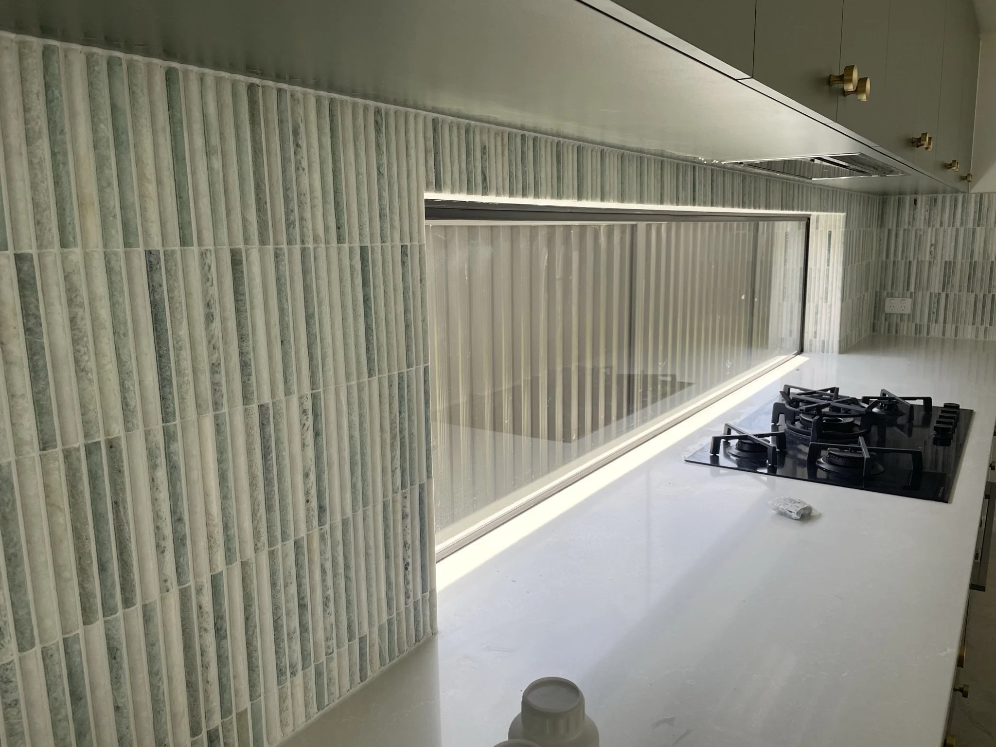 Modern kitchen with window, backsplash tiles, gas cooktop, and countertop.