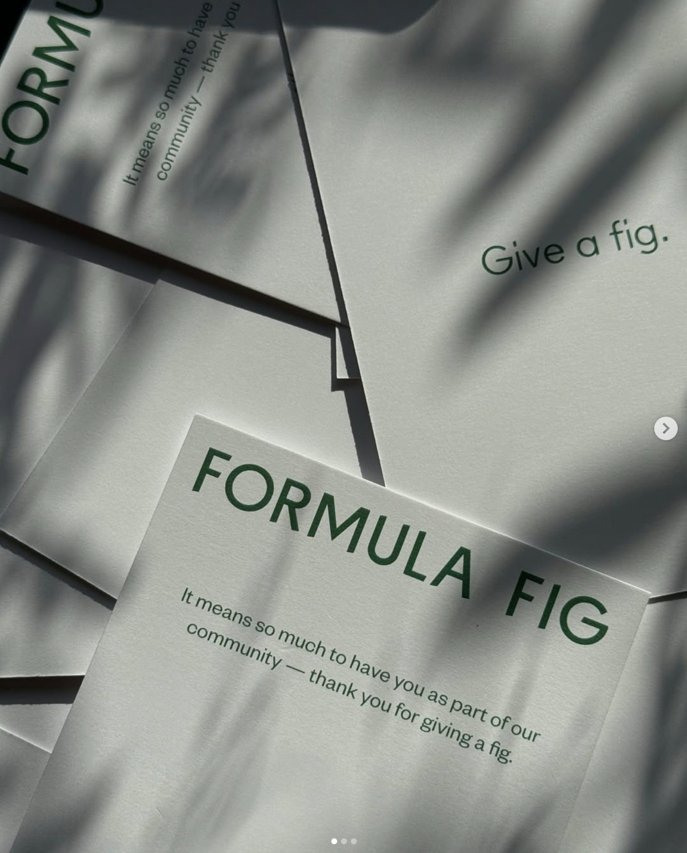 Multiple sheets of paper with the phrase 'FORMULA FIG' in bold green letters and a message explaining that giving a fig is part of the community, with shadows cast across the papers.