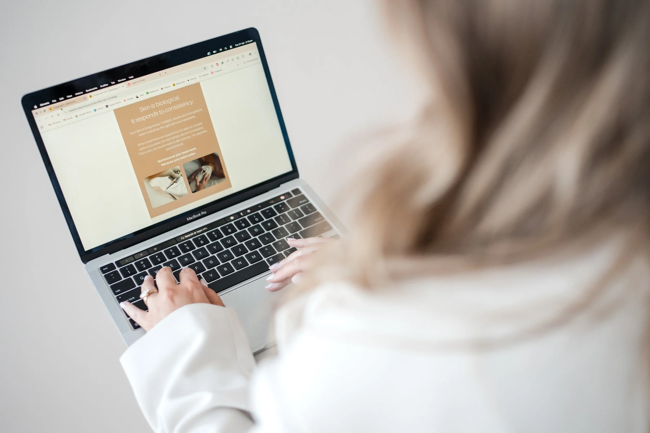 Person wearing white long sleeve shirt using a MacBook Pro laptop on a white table.