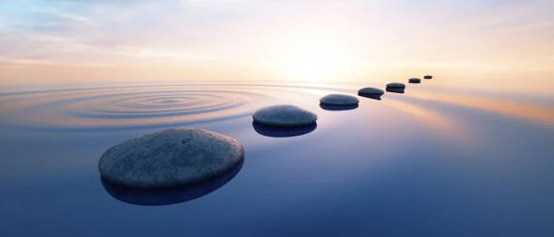 Smooth stepping stones arranged in a straight line on calm water at sunset