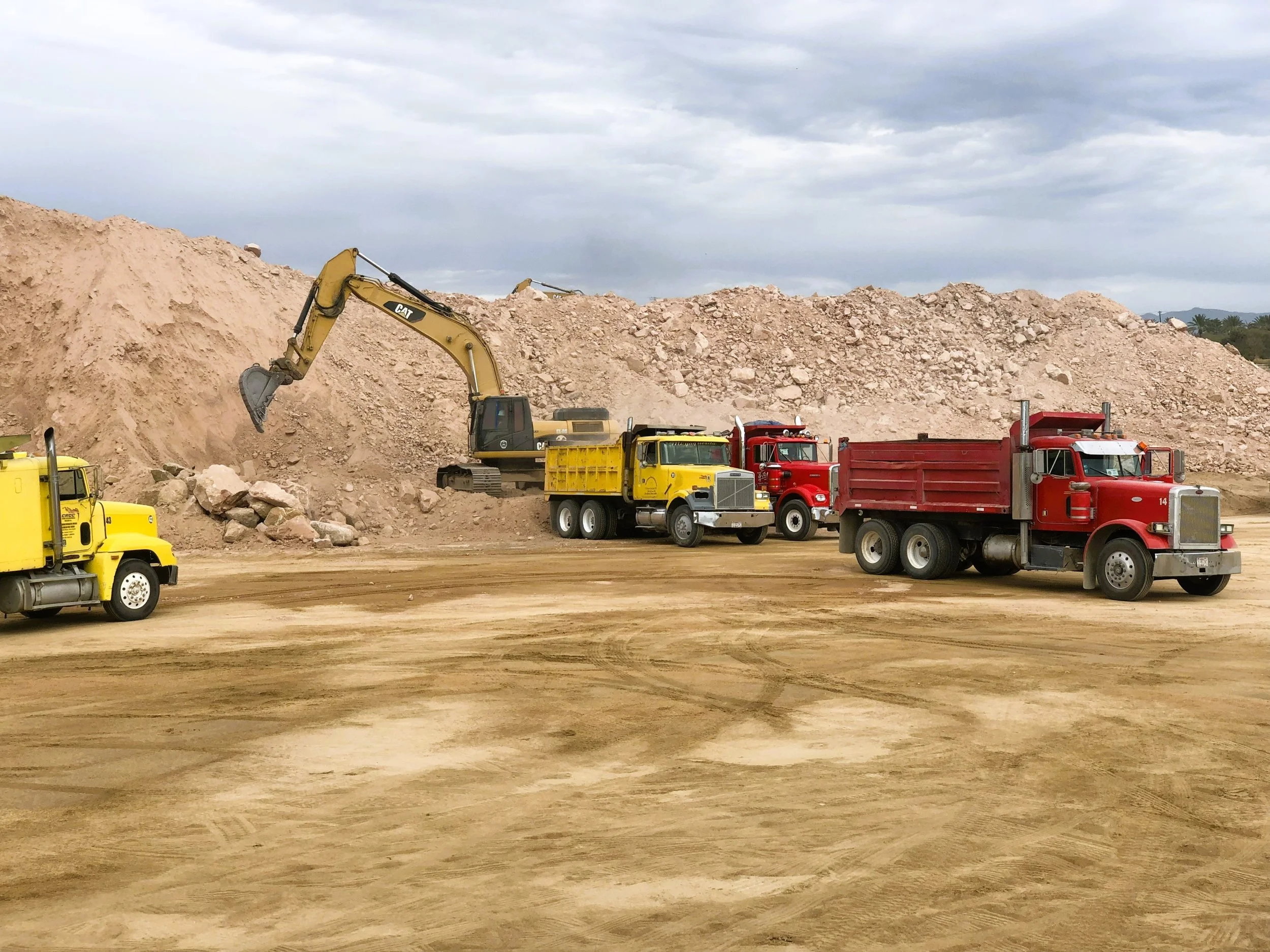 camiones de volteo recibiendo carga de material producto de excavaciones mediante una excavadora caterpillar
