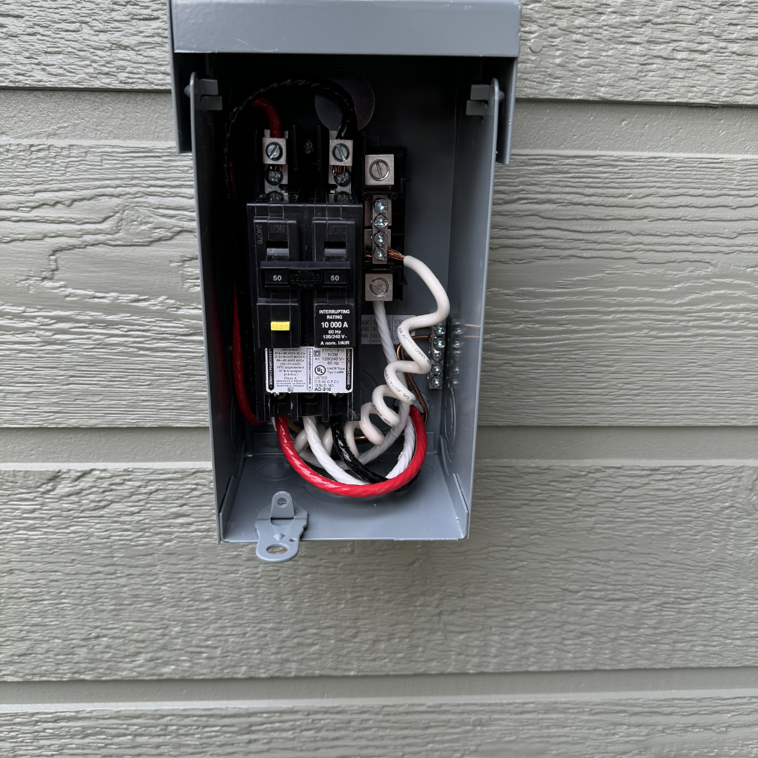 Open electrical box with circuit breaker and wiring inside, mounted on an exterior wall with horizontal siding.