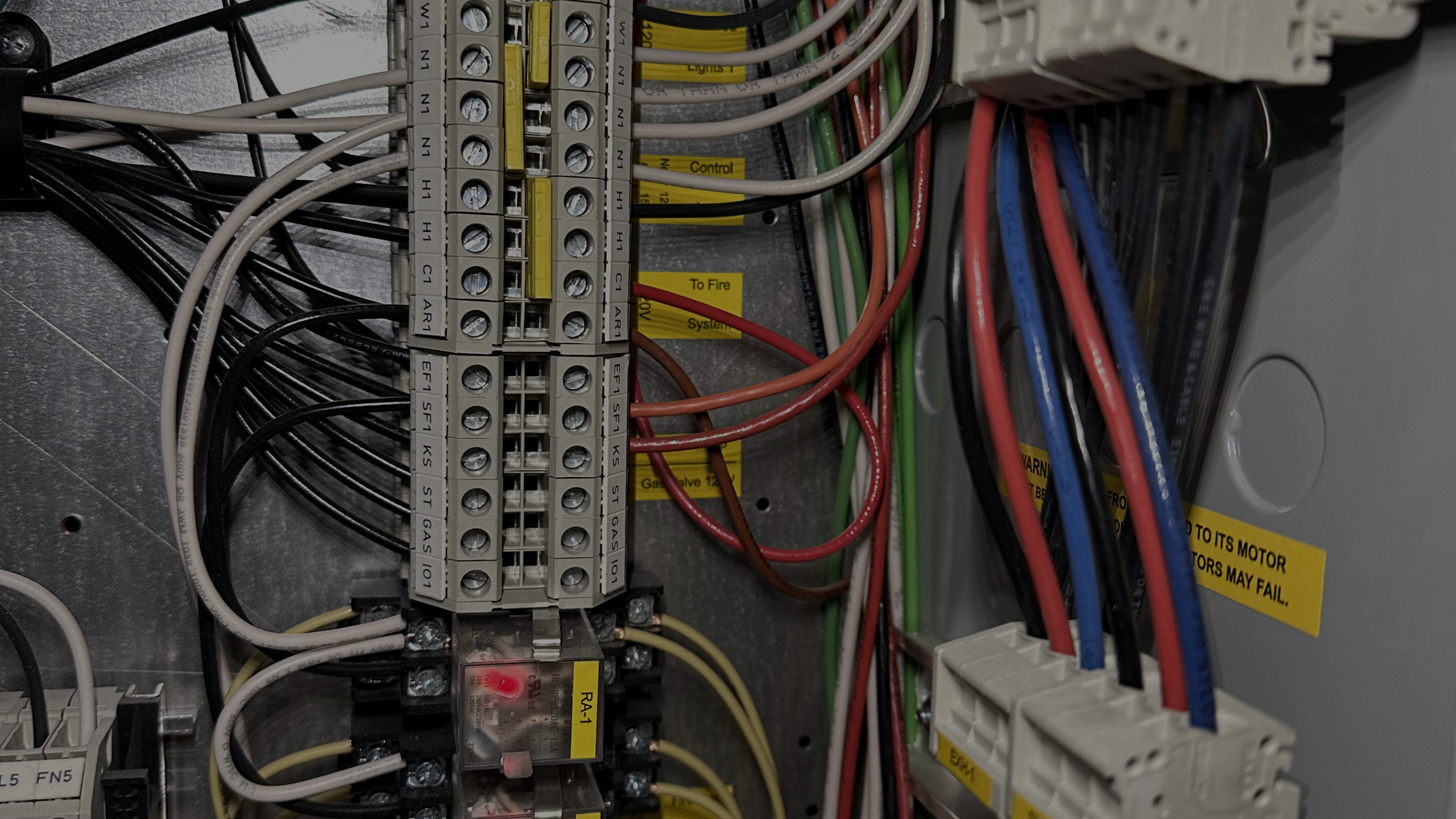 Electrical control panel with various wires, circuit breakers, and labels.