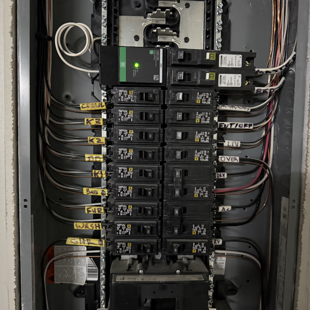 Electrical breaker panel with multiple breaker switches labeled with various home appliance names and wires connected.