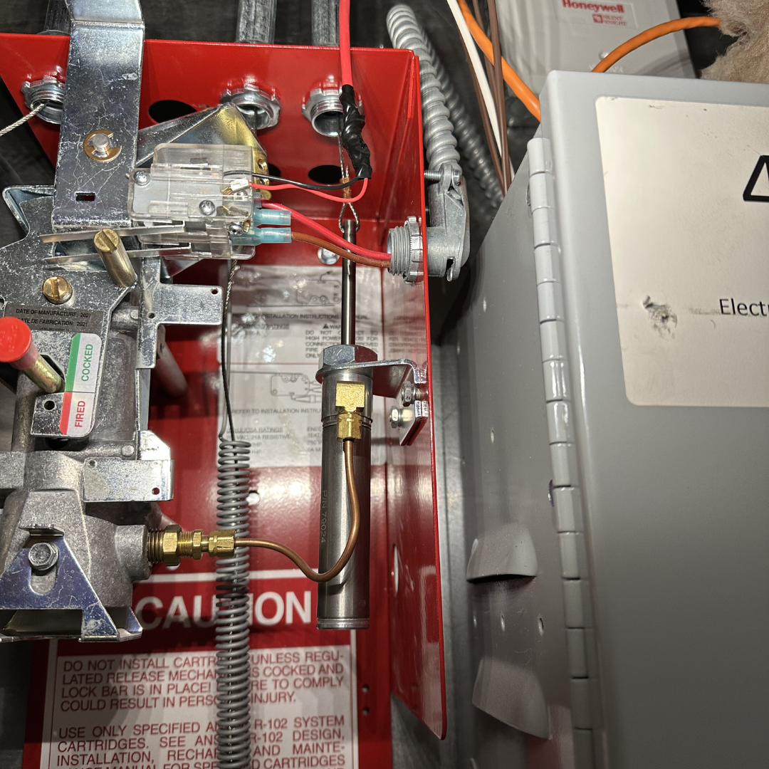 Close-up of an electrical panel with wiring, metal components, and a red warning label.