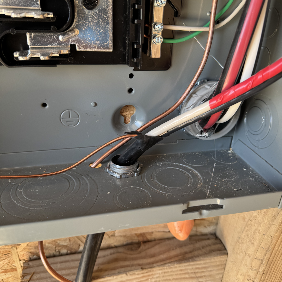 Interior view of an electrical panel with wires and components inside a metal box.