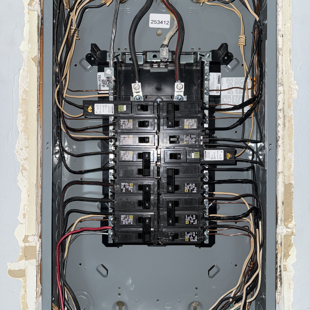 Electrical breaker box with multiple switches and wires inside a metal panel.
