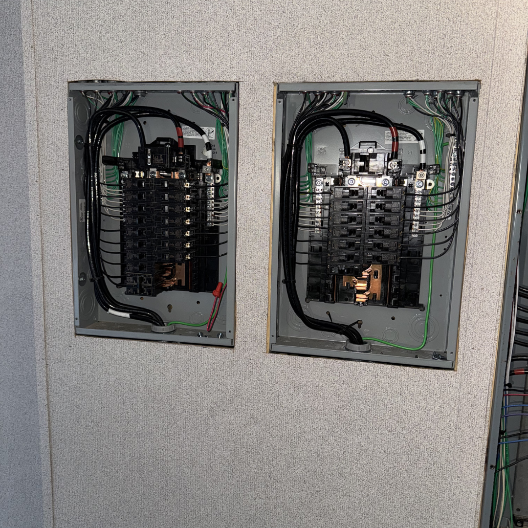Open electrical breaker panels with wires and circuit breakers inside.