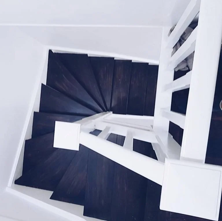 Top-down view of a spiral staircase with dark wood steps and white railing