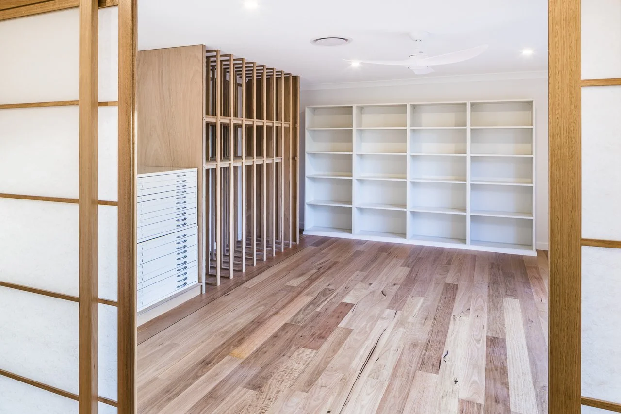 Art Studio with white built-in bookshelves, wooden floor, wooden partition, and ceiling fan.