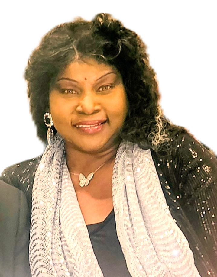 A woman with curly black hair and light makeup, wearing a black sequin jacket, a silver scarf, butterfly necklace, and earrings, smiling at the camera.