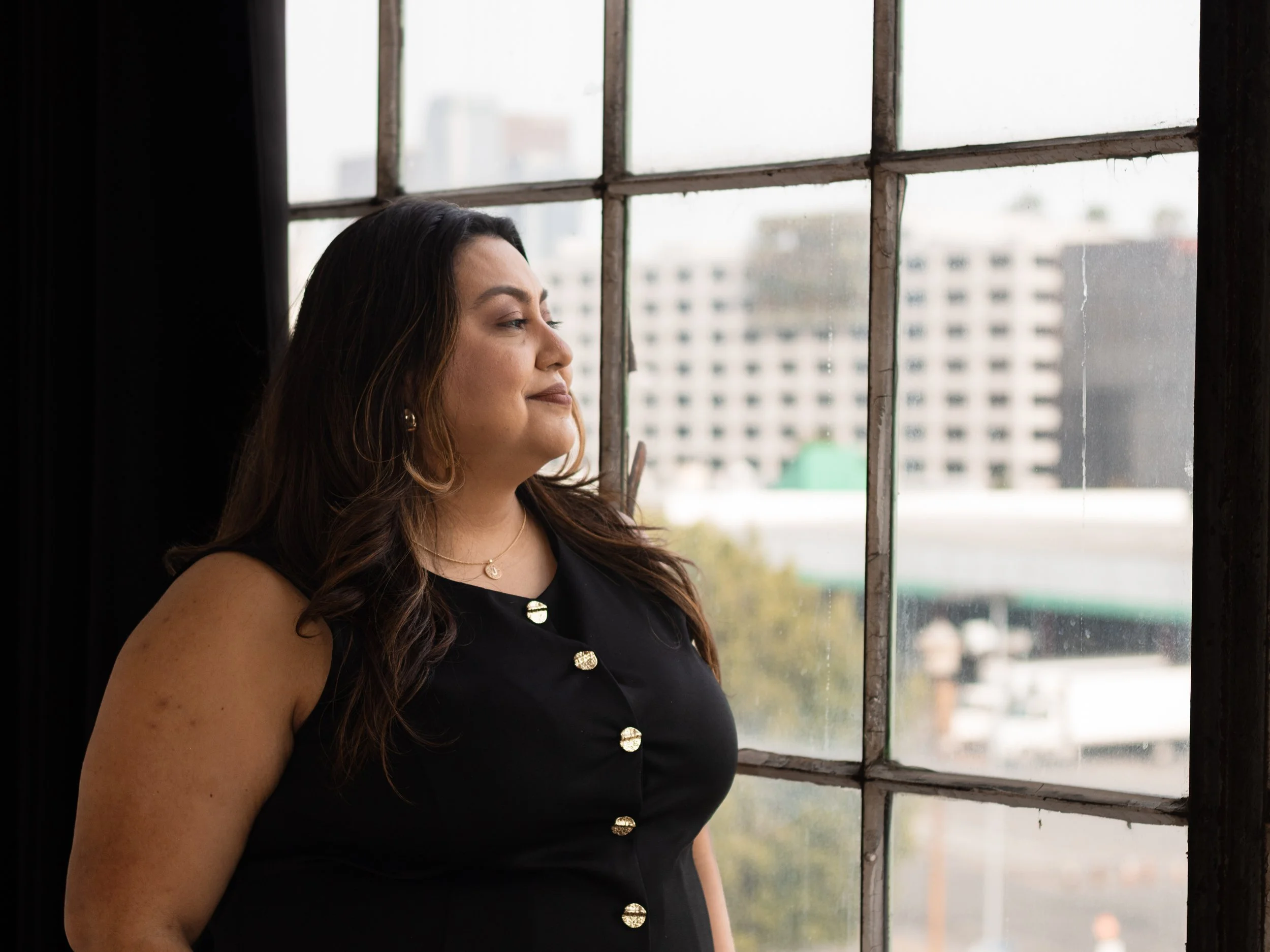 Joanna, creative director, looking out the window to LA city landscape for branding shoot