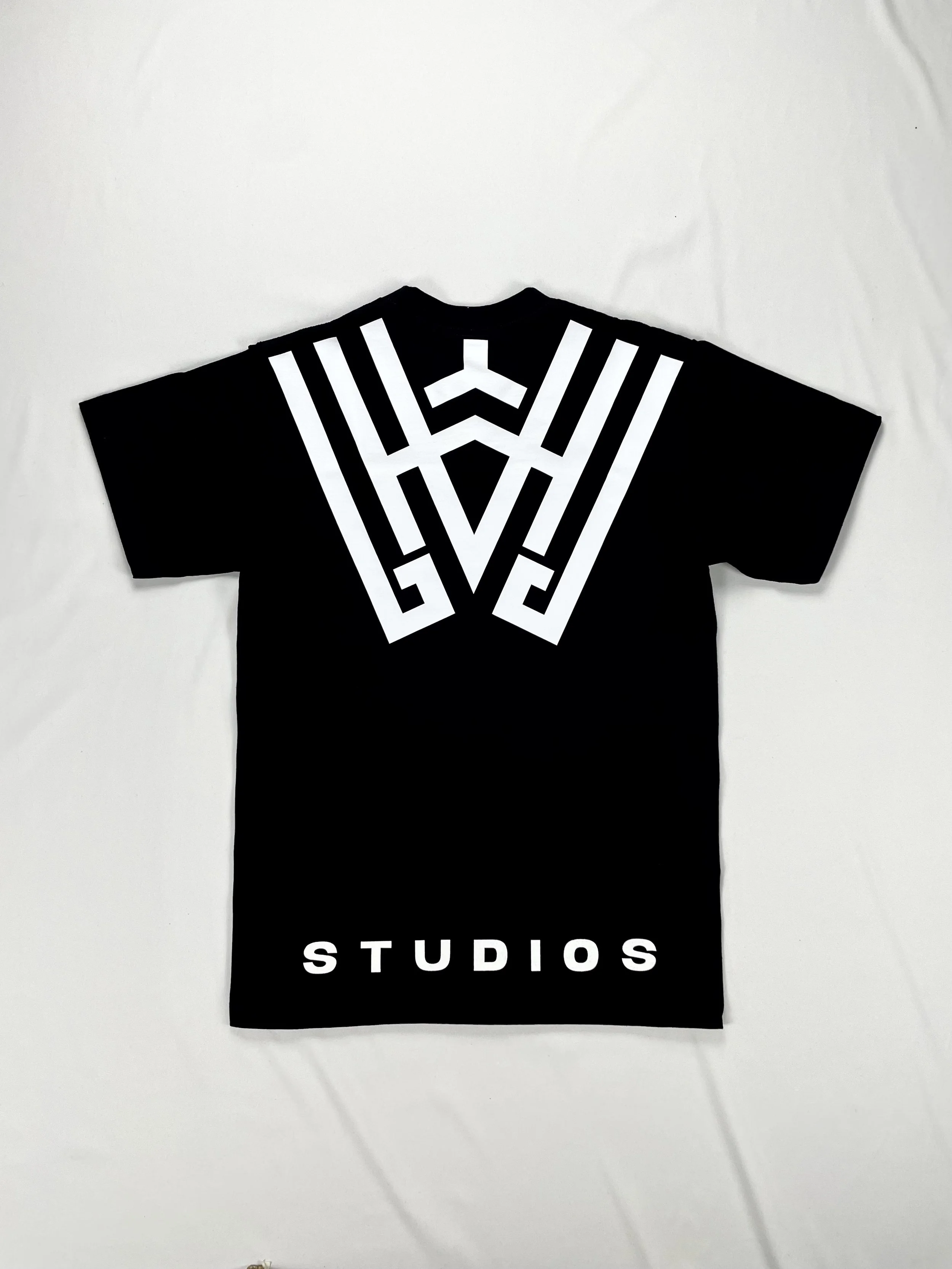 Black T-shirt with white geometric design on the back and the word "STUDIOS" printed at the bottom.