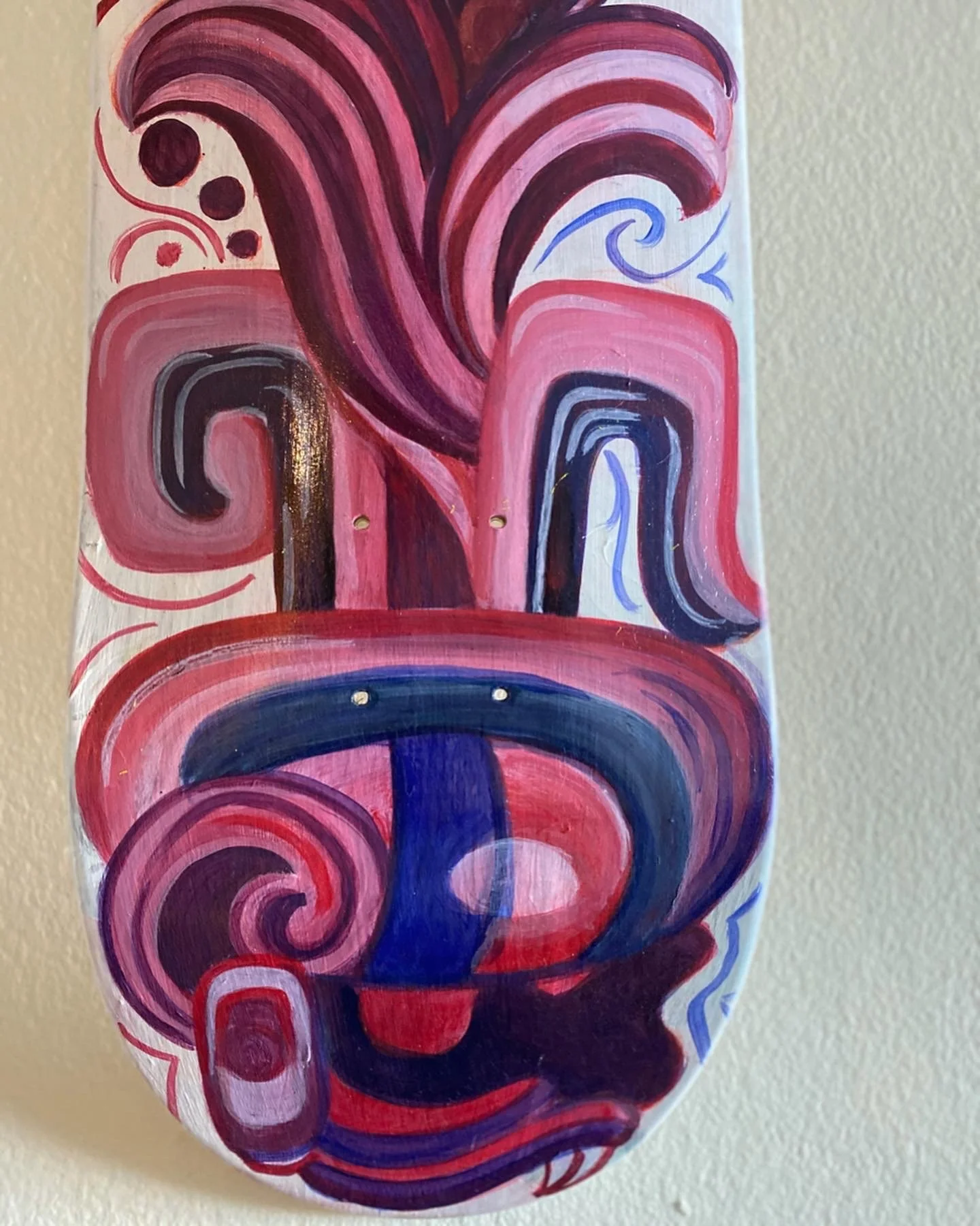 Colorful abstract painting on a skateboard deck featuring swirling patterns in pink, red, purple, and blue.