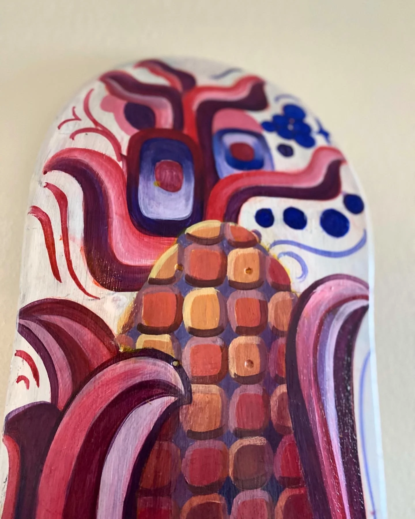 Close-up of a painted wooden surface with colorful abstract designs in shades of red, purple, pink, orange, and blue.