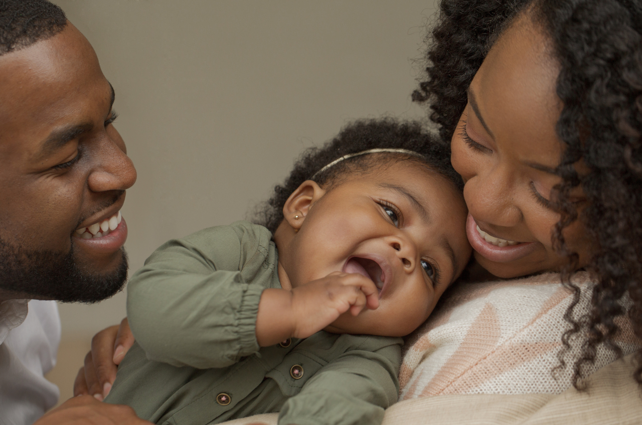 Close-up of a happy family with a mother, father, and young daughter, smiling and enjoying a joyful moment together indoors.
