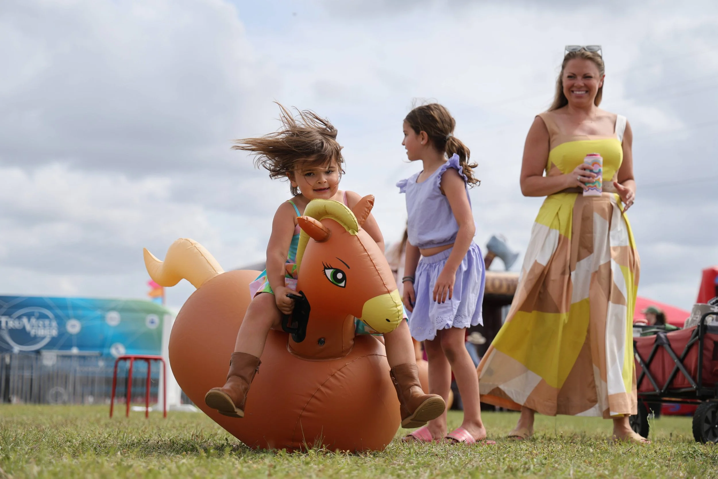 Emma Hobbs, age 4, rides on a blowup horse while her mother, Lauren, watches her in the Truvista Kid’s Zone. Although this is Emma’s first time attending the Cup, her parents have come out to the race course ever since they met college.