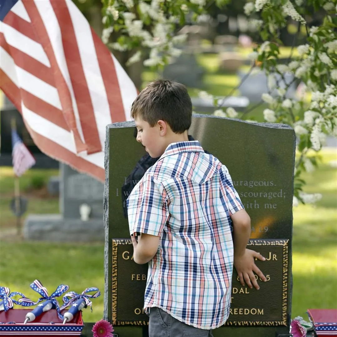 Myles Eckert, 9, leans on his father Andy Eckert's tombstone.