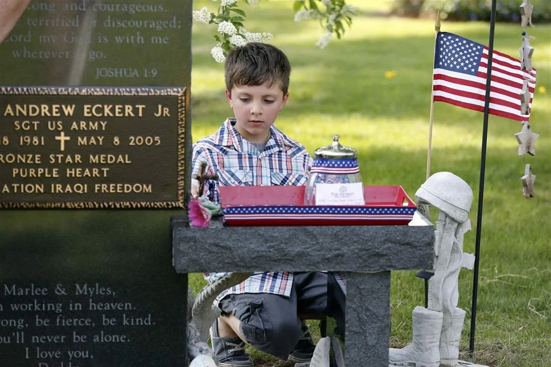 Myles Eckert, 9, replaces a cross on his father Andy Eckert's tombstone.