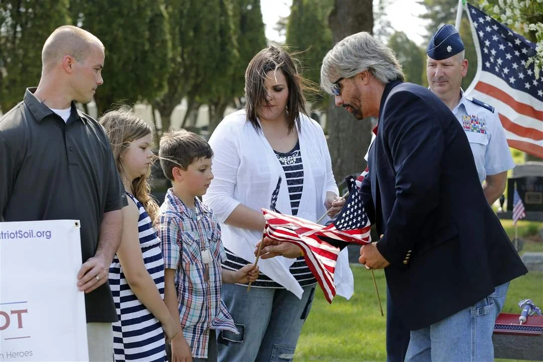 Kentuckyana Jones, from A&E television, presents American flags to Marlee Eckert, 10, Myles Eckert, 9, and Tiffany Eckert, as Sgt. Jeremy Langham, left, and Lt. Col. Frank Dailey, right, look on.