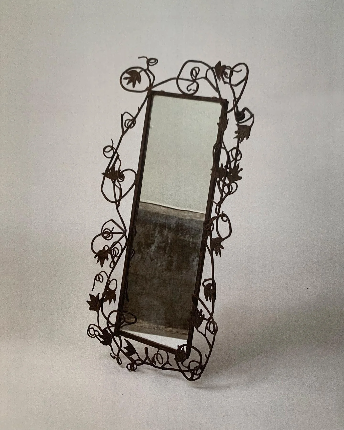 Decorative full-length mirror with a frame made of iron vines and leaves.