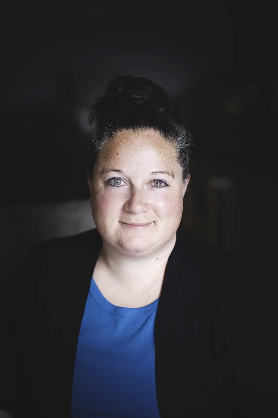 Portrait de Traci, femme aux cheveux gris avec yeux bleu. Elle porte un t-shirt noir.