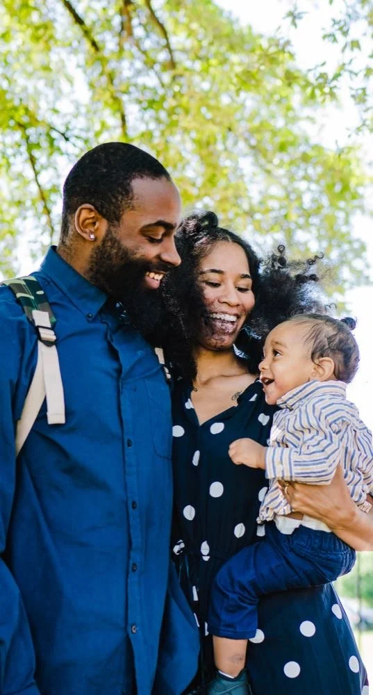 Des parents et leur enfant adopté, ils sourient en se promenant dans un parc