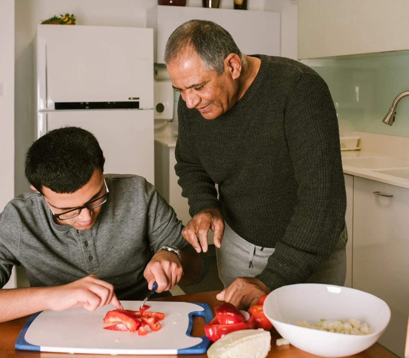 père qui aide son fils adoptif à cuisiner