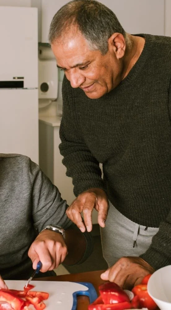 Un père et son fils adoptif dans la cuisine qui regarde en livre ensemble