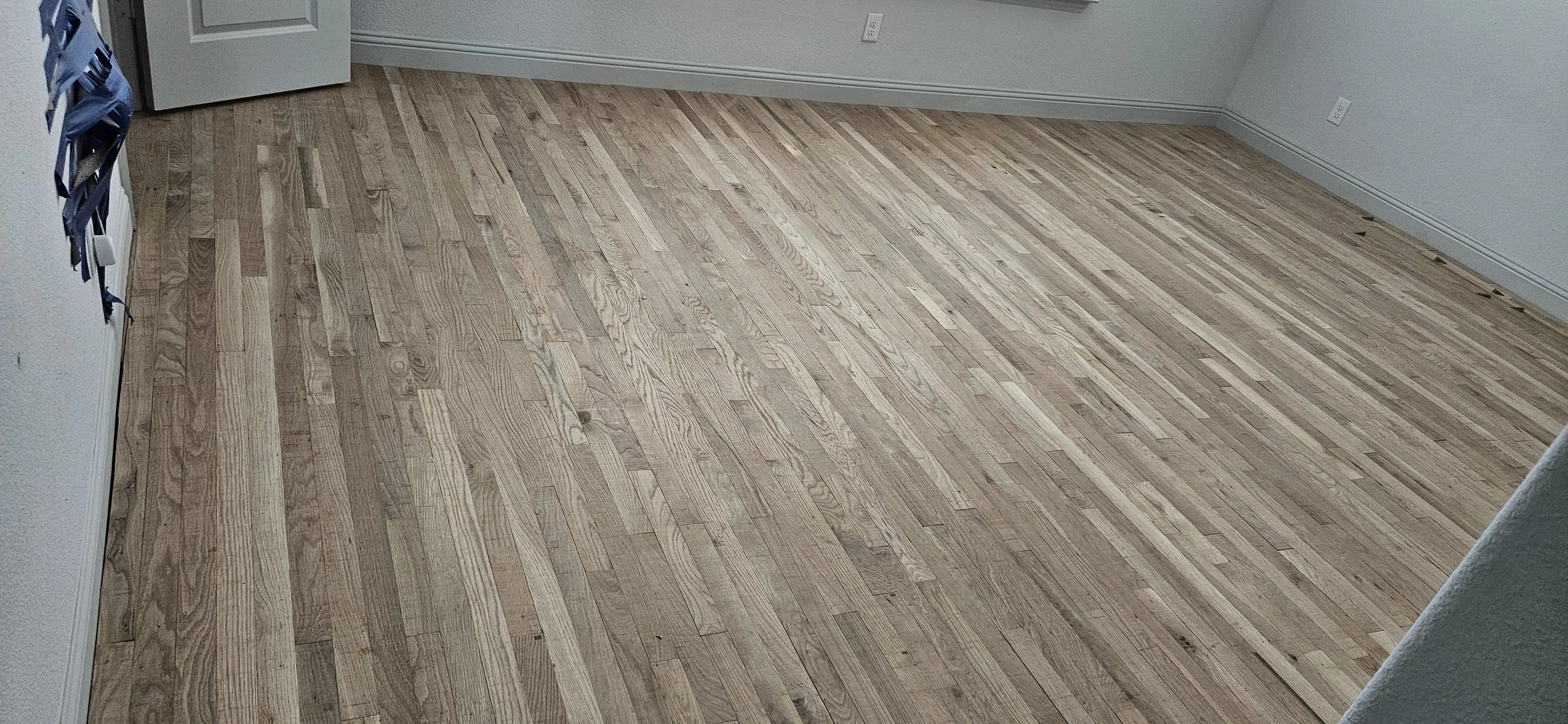 Empty room with light-colored wooden flooring, white walls, and multiple electrical outlets.
