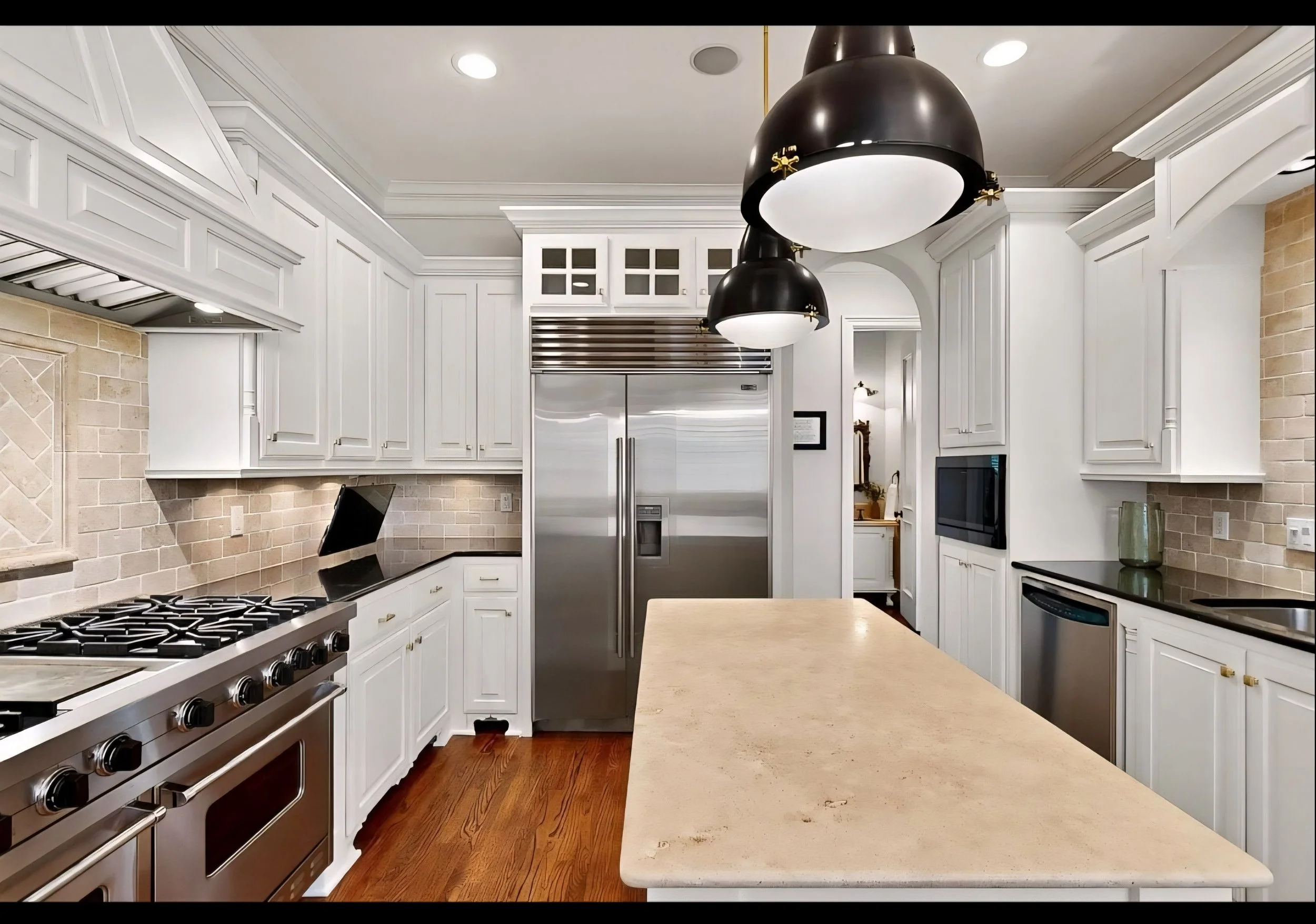 A modern kitchen with white cabinets, black pendant lights, stainless steel appliances, a beige island countertop, and wooden flooring.