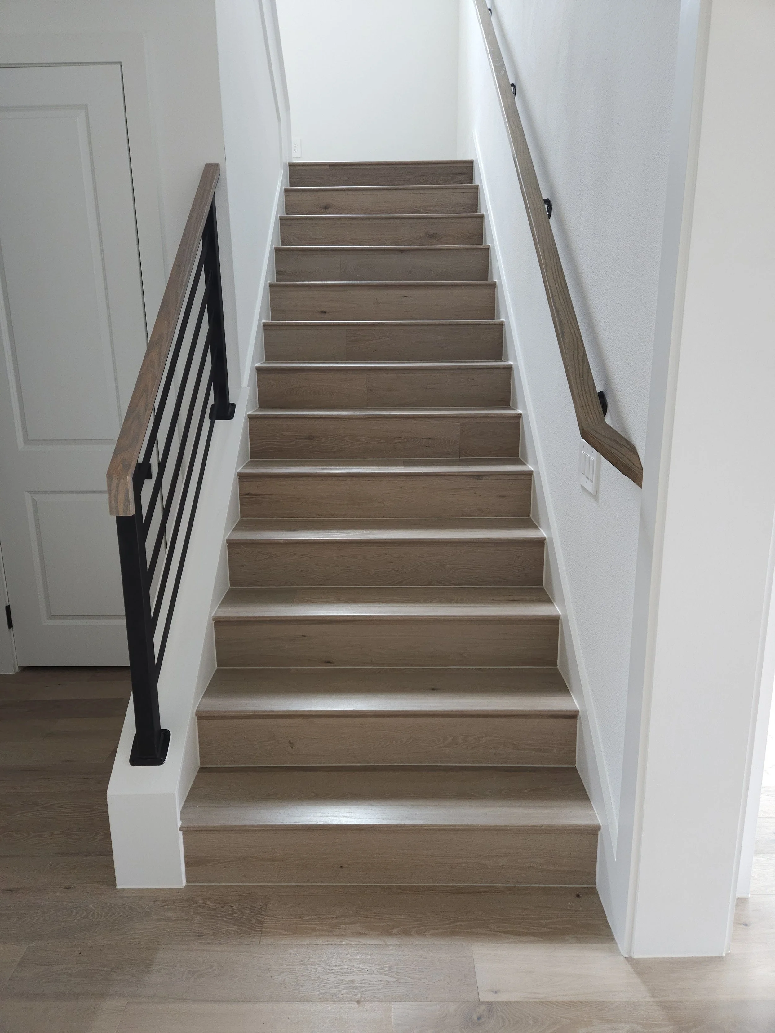 Photo of wooden staircase with black and wood handrails in a modern home.