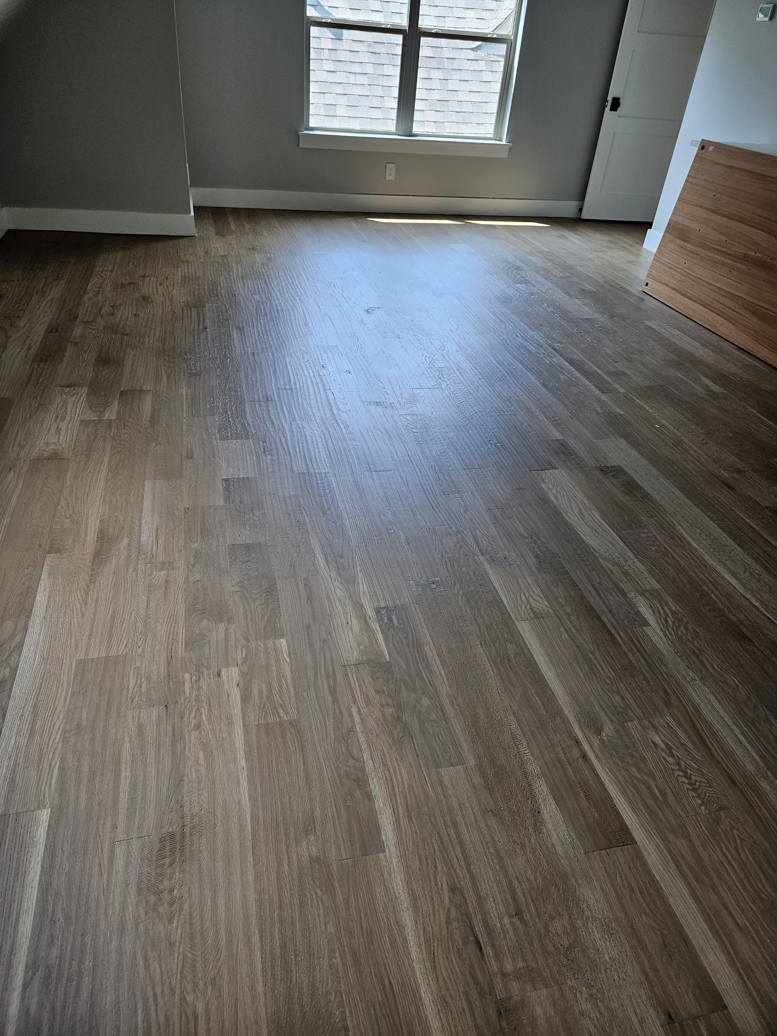 Empty room with hardwood floors, windows, and a door.