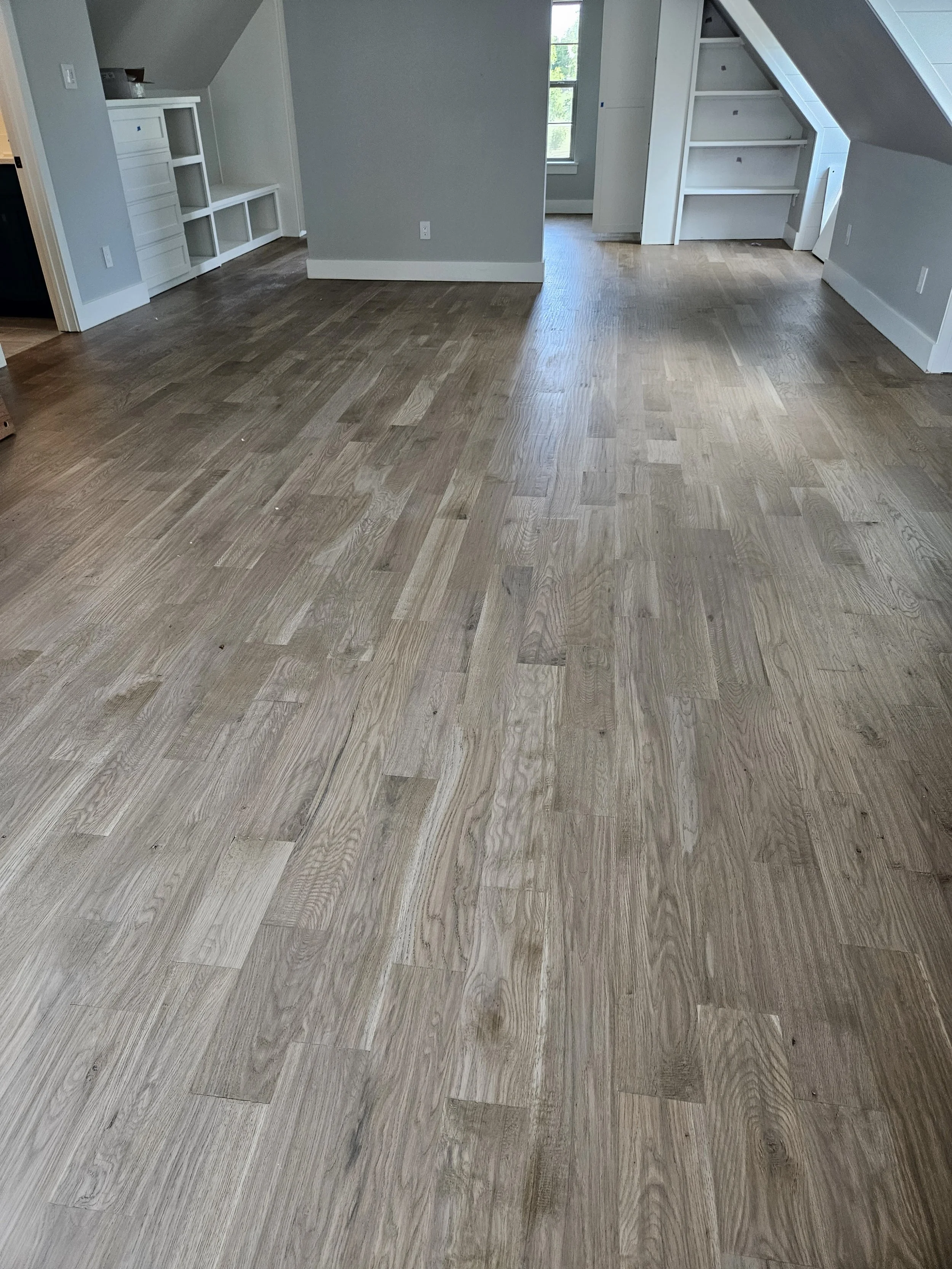 Empty room with wood flooring and built-in shelves on the walls.