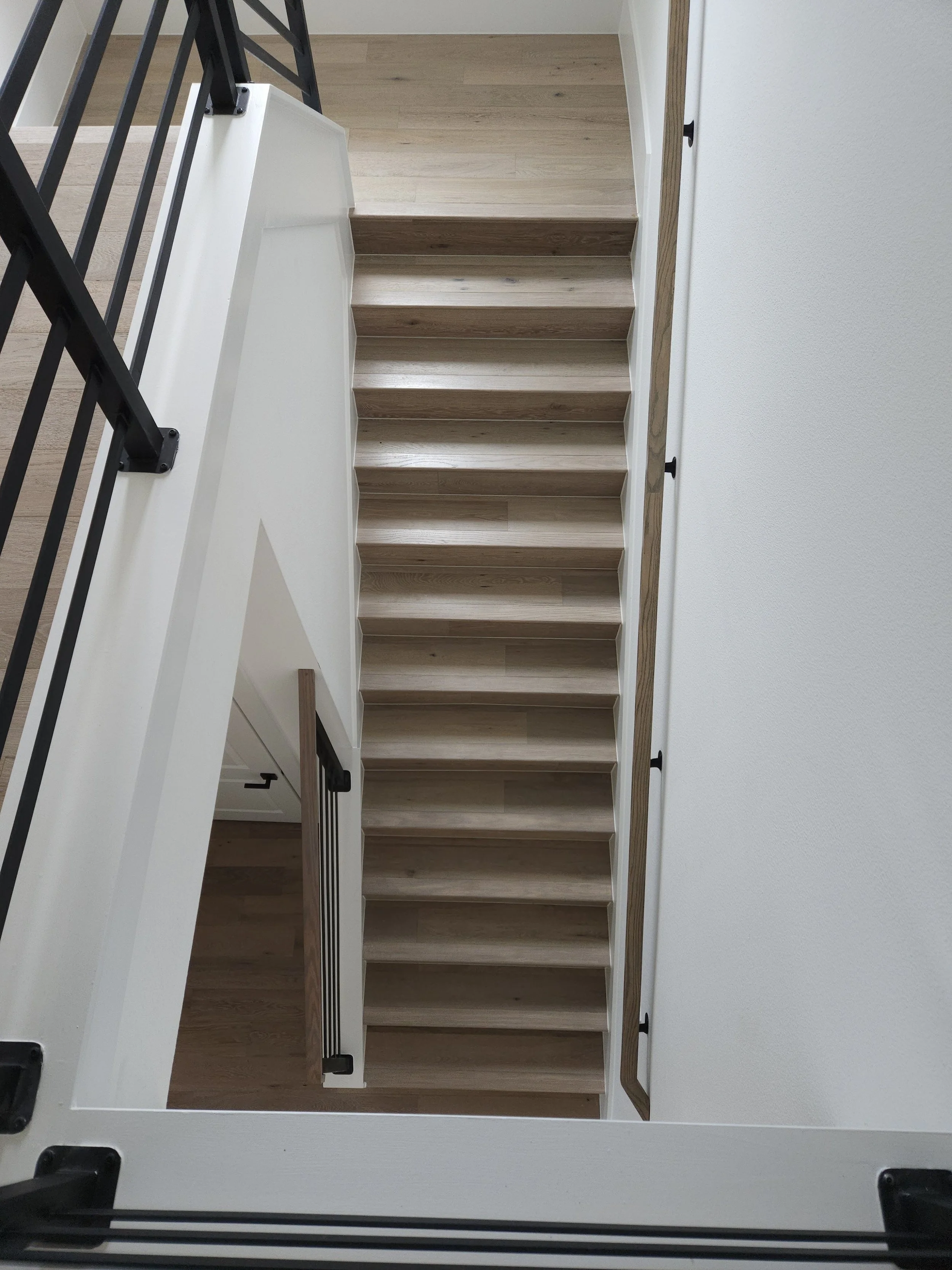 Top view of a wooden staircase with black metal railing.