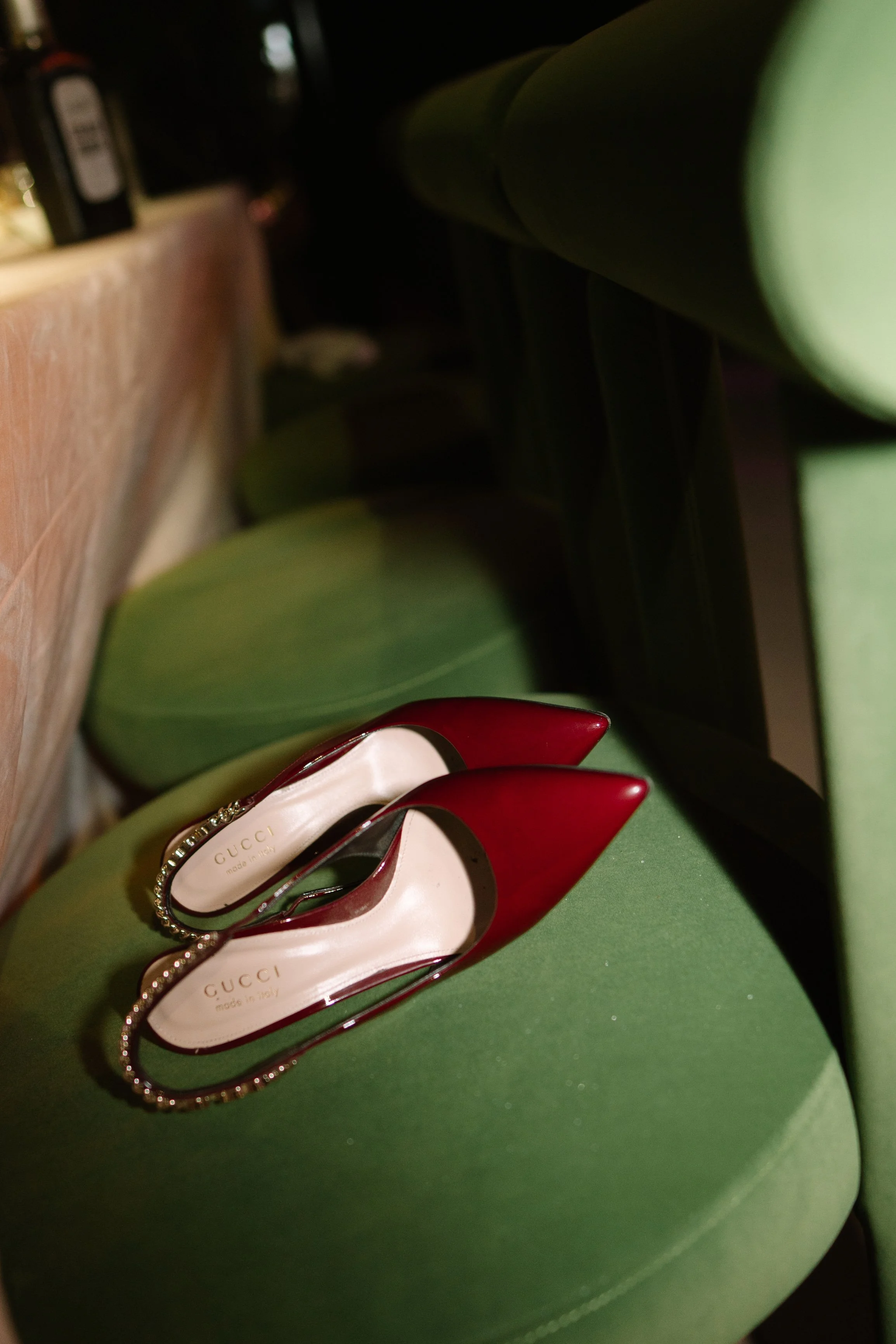 Red Gucci high-heeled shoes with pearl-embellished straps on a green seat. Wedding Photography in Valle de Guadalupe, Ensenada, Baja California.