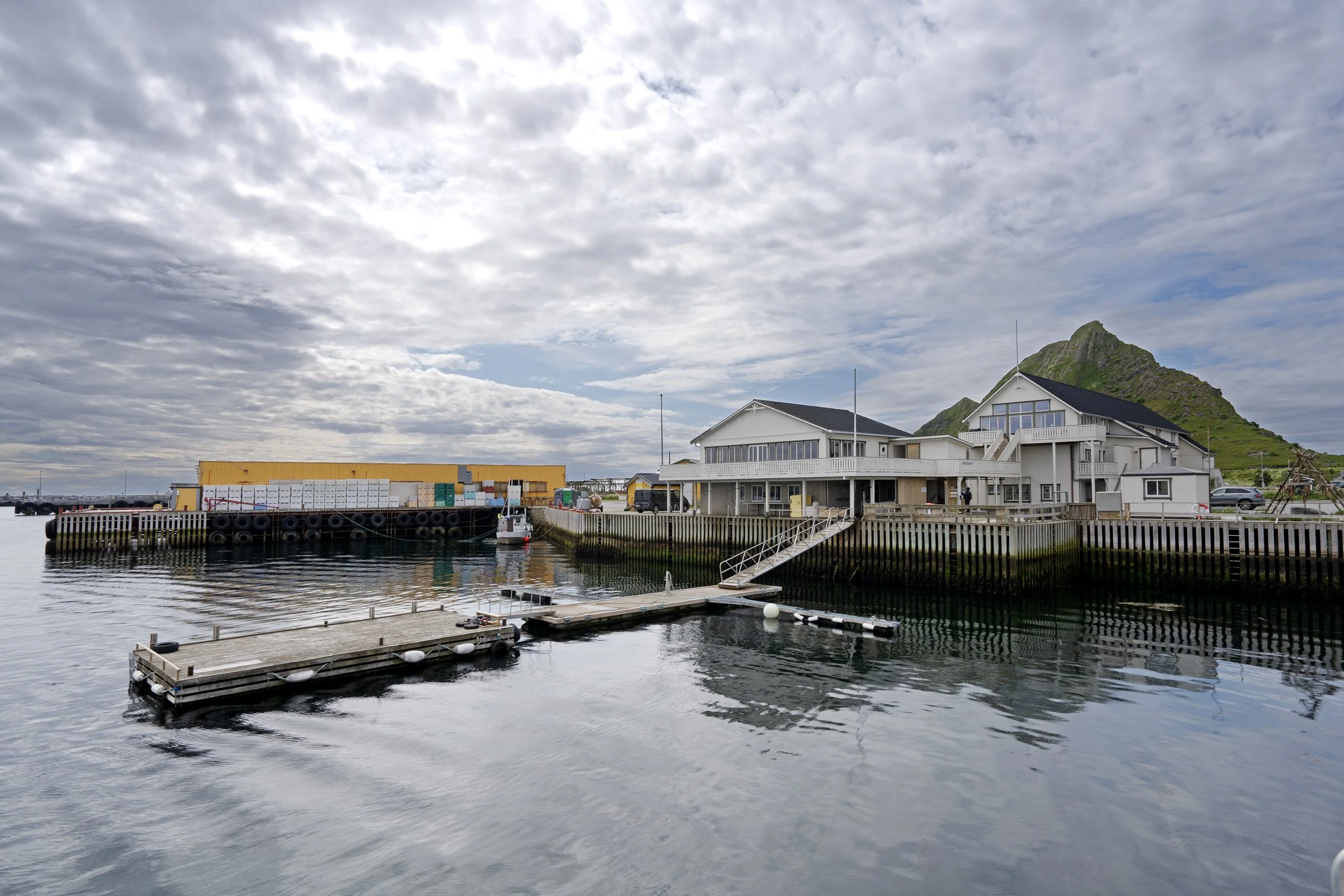 Docks and boats in a harbor with a mountain in the background on a cloudy day.