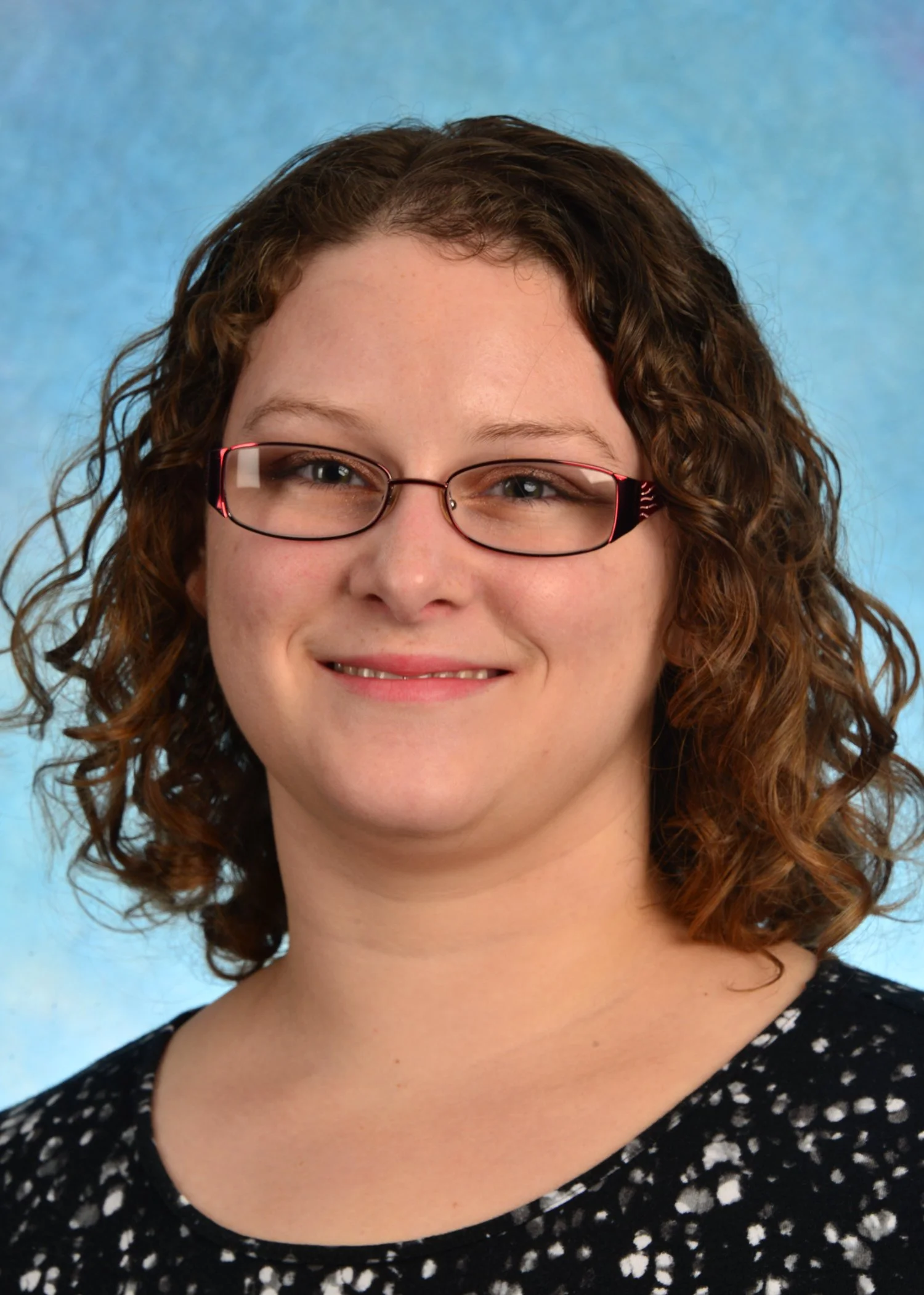 A professional headshot of Dr. Engle, a female with light-colored skin, curly brown hair, and glasses.