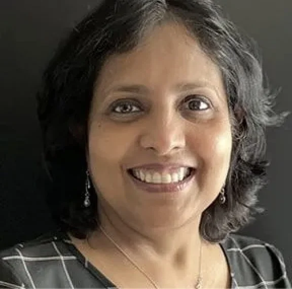 Close-up of a woman with dark hair, smiling, wearing earrings and a black and white striped top.