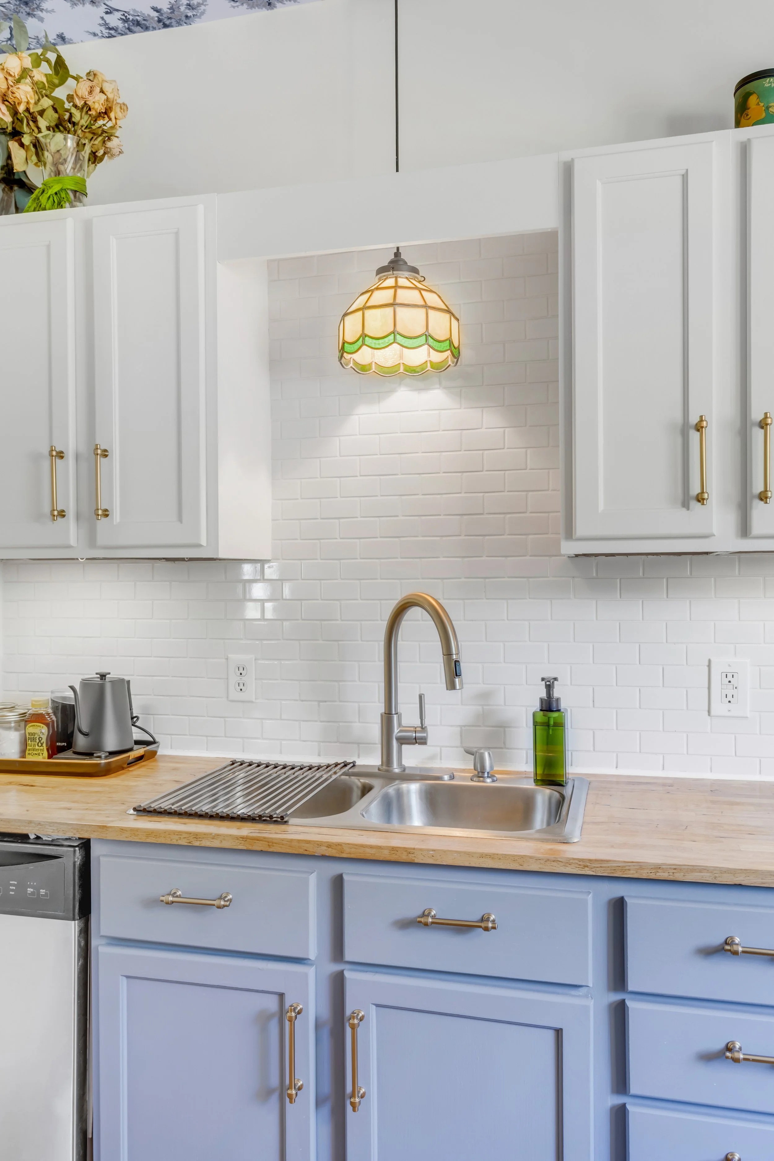 Stained glass bistro light frames out custom blue cabinets with bronze hardware.