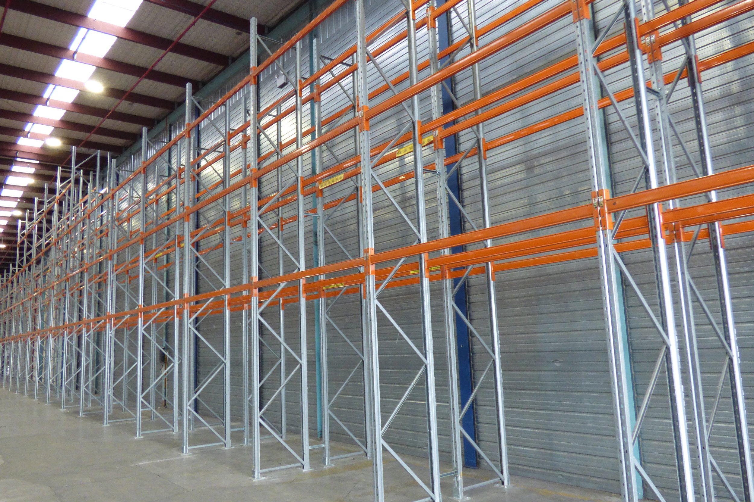 Empty industrial warehouse with tall metal storage racks and shelves.
