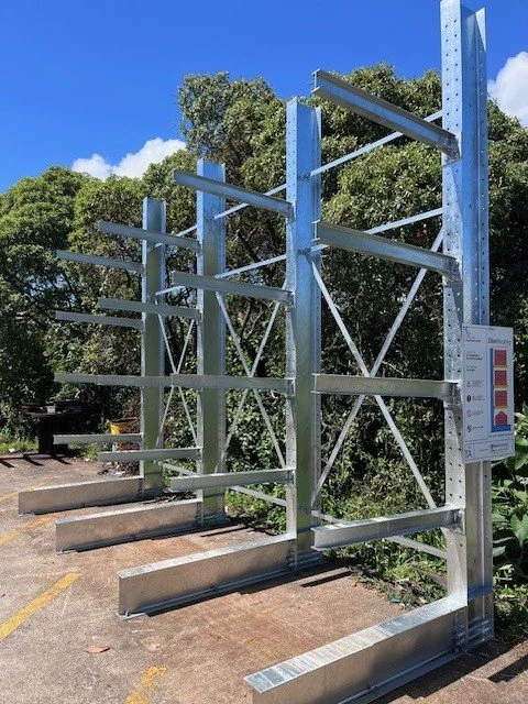 Empty metal retail display racks outdoors with a blue sky and trees in the background.