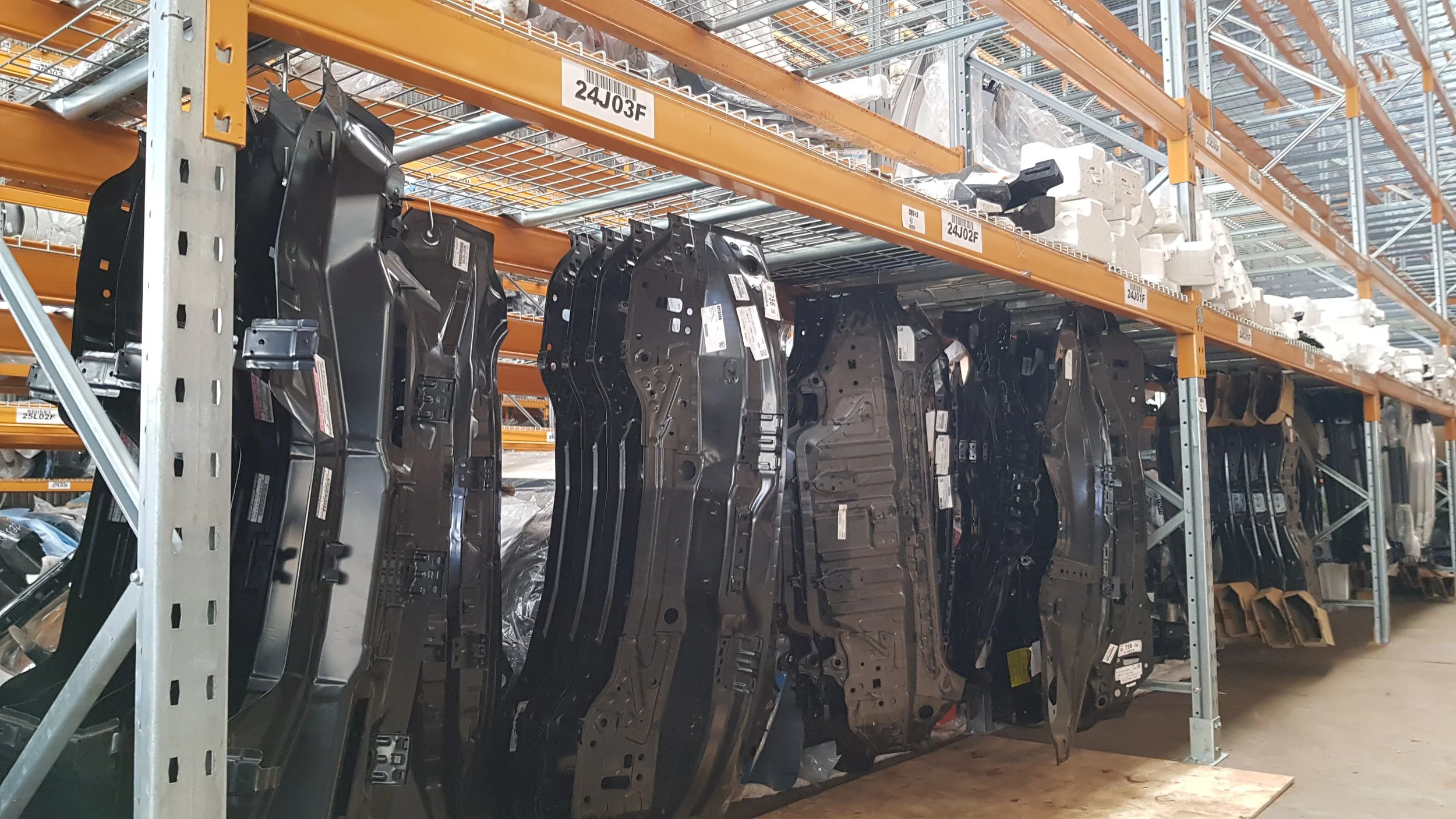 Industrial warehouse shelving with car parts and foam packaging materials.