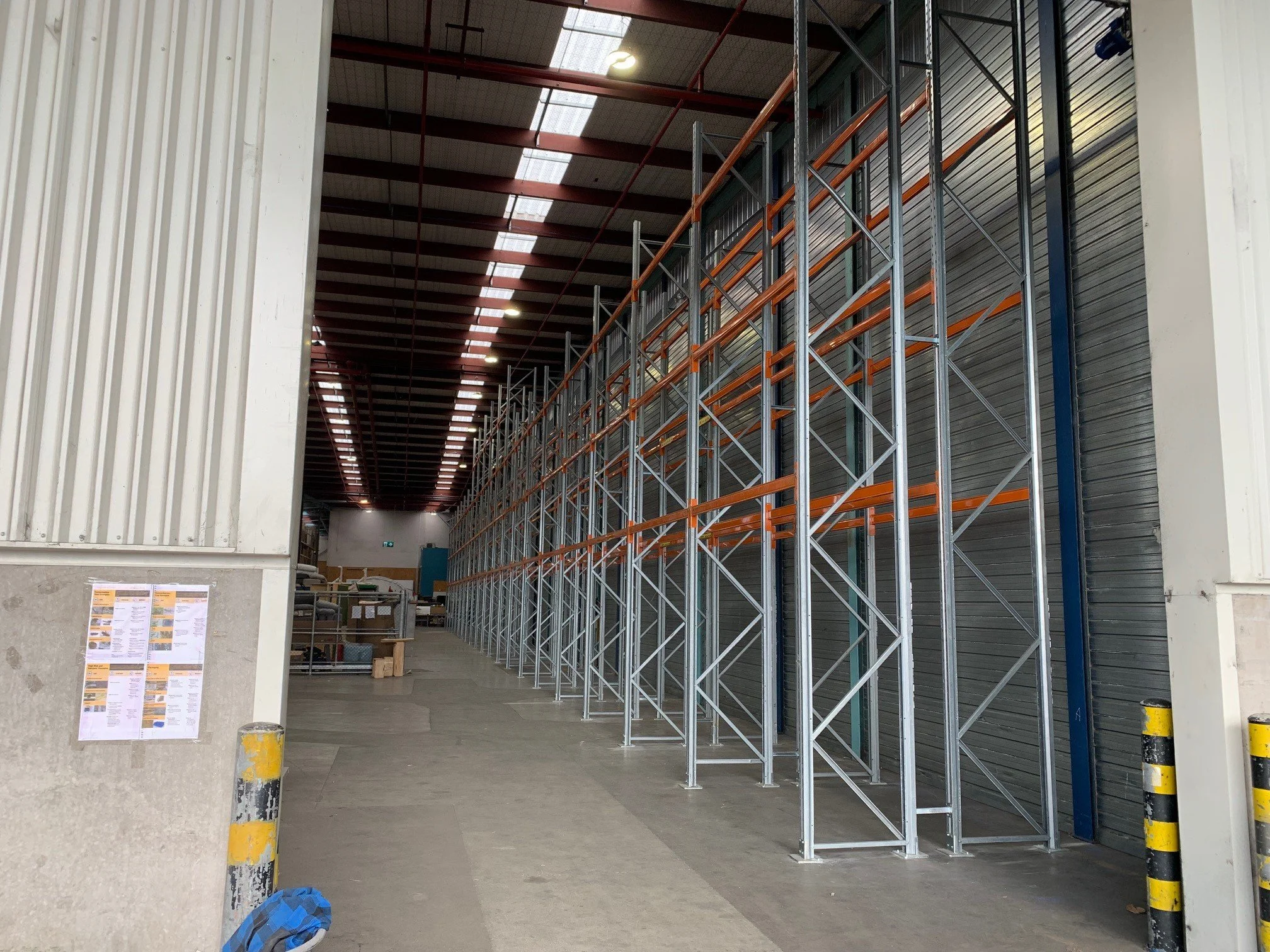 Empty warehouse with metal shelving units and a large roll-up door on the right side.